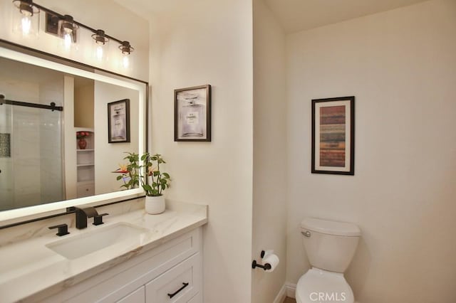 bathroom with a shower with shower door, toilet, and vanity