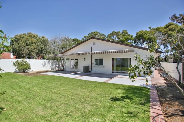 rear view of house featuring cooling unit, a lawn, and a patio