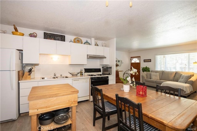 kitchen with white appliances, light wood-type flooring, a textured ceiling, white cabinets, and sink