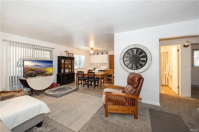 living room with ceiling fan, a textured ceiling, and light carpet