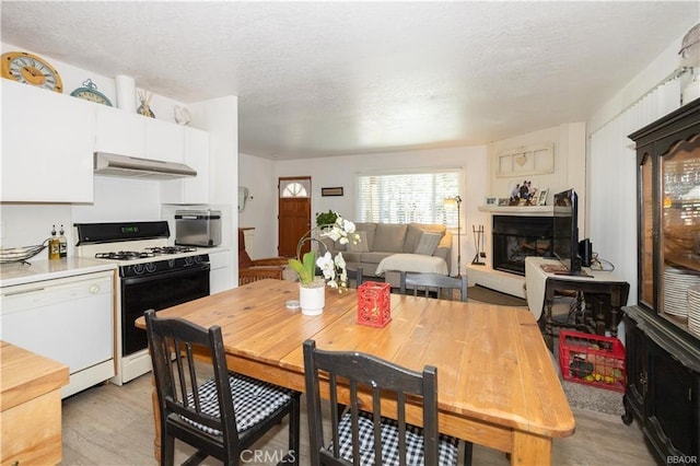 kitchen with range with gas stovetop, light hardwood / wood-style flooring, white cabinets, and white dishwasher