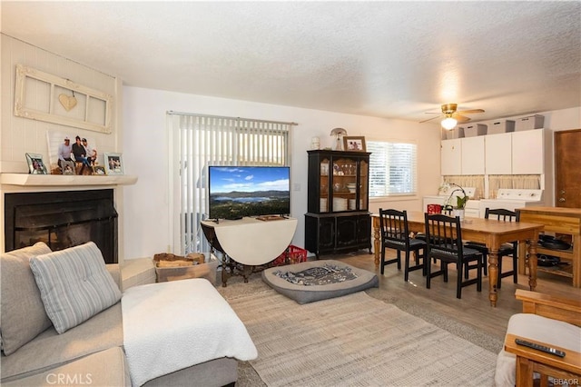 living room with a textured ceiling, ceiling fan, and hardwood / wood-style floors