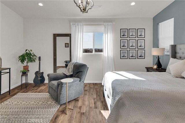 bedroom featuring an inviting chandelier, recessed lighting, wood finished floors, and visible vents