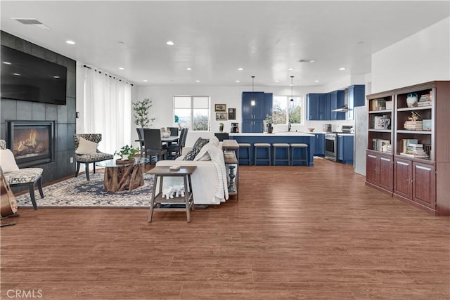 living area featuring dark wood-style flooring, a fireplace, visible vents, and recessed lighting