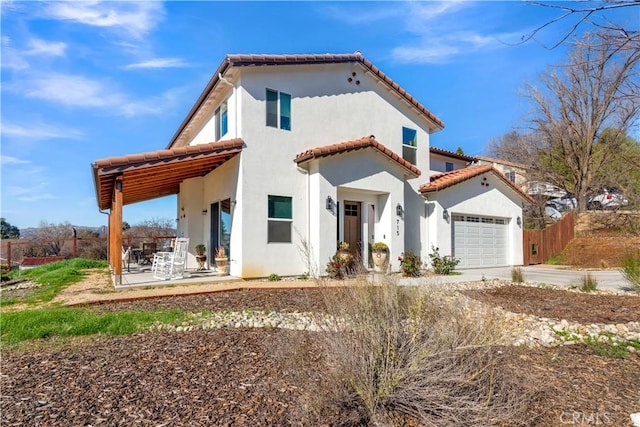 mediterranean / spanish house with a tile roof, stucco siding, an attached garage, a patio area, and fence