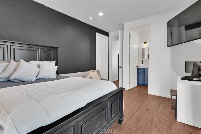 bedroom featuring recessed lighting, baseboards, ensuite bathroom, and light wood-type flooring