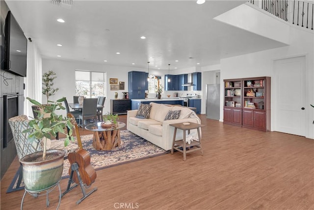 living area with recessed lighting, visible vents, a fireplace, and light wood finished floors