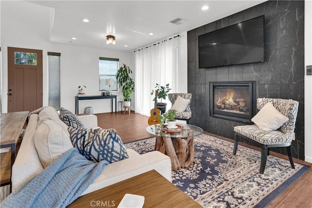 living room featuring a large fireplace, visible vents, wood finished floors, and recessed lighting