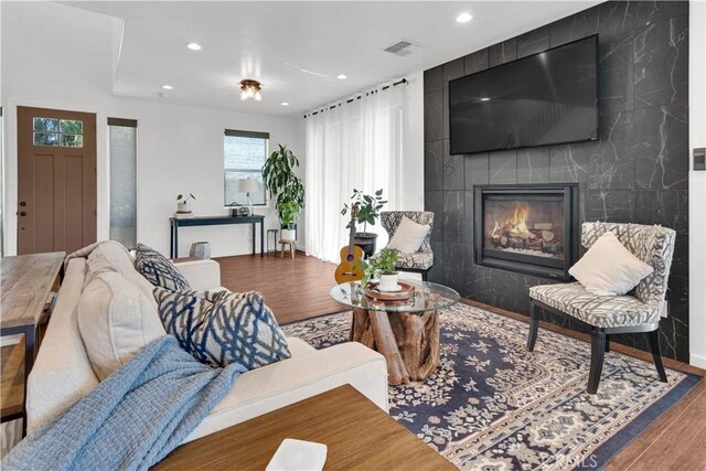 living area with recessed lighting, an accent wall, wood finished floors, and visible vents