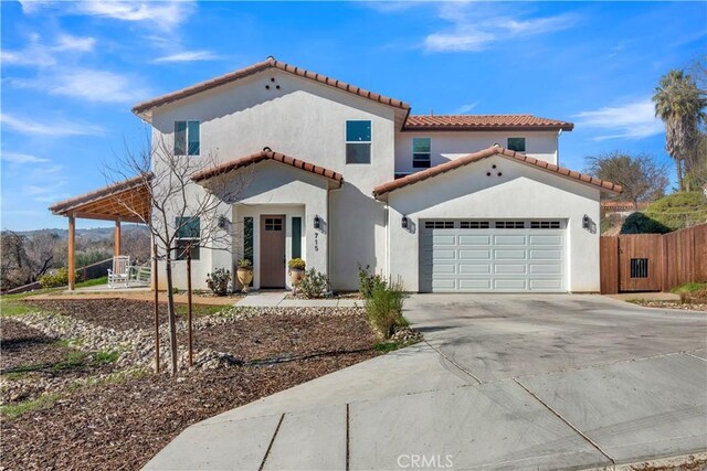 mediterranean / spanish home featuring a garage, fence, stucco siding, a tiled roof, and driveway
