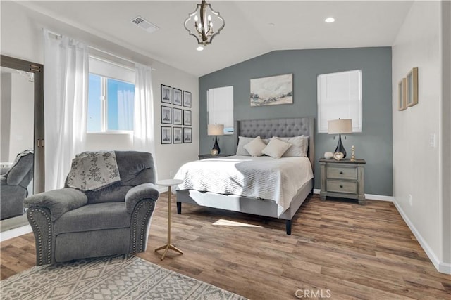 bedroom with visible vents, an inviting chandelier, vaulted ceiling, wood finished floors, and baseboards