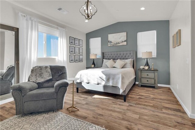 bedroom featuring visible vents, wood finished floors, lofted ceiling, and an inviting chandelier