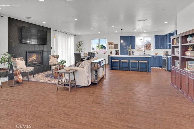 living room with a healthy amount of sunlight, a large fireplace, light wood-style floors, and recessed lighting