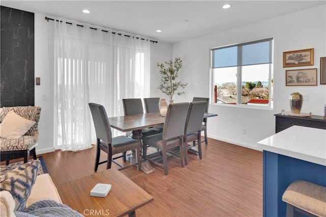 dining space with baseboards, wood finished floors, and recessed lighting