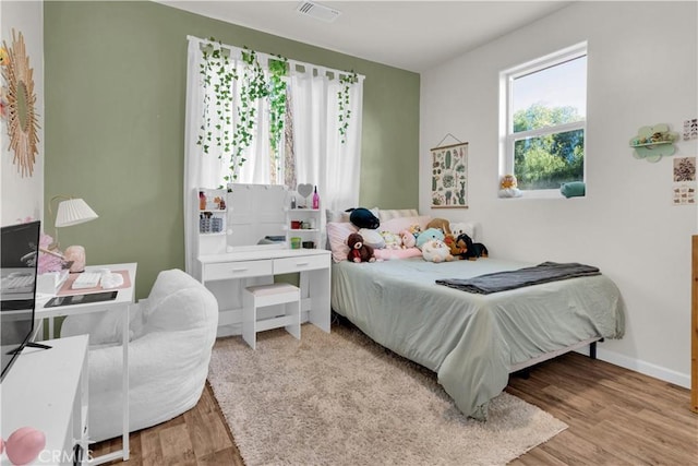 bedroom with wood finished floors, visible vents, and baseboards