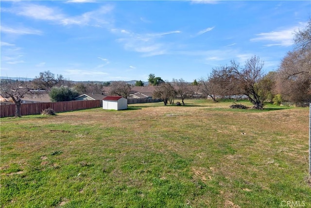 view of yard featuring a shed, fence, and an outdoor structure