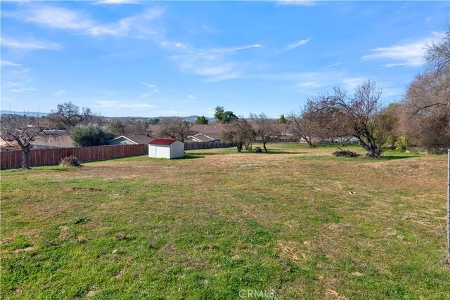 view of yard with fence, an outdoor structure, and a shed