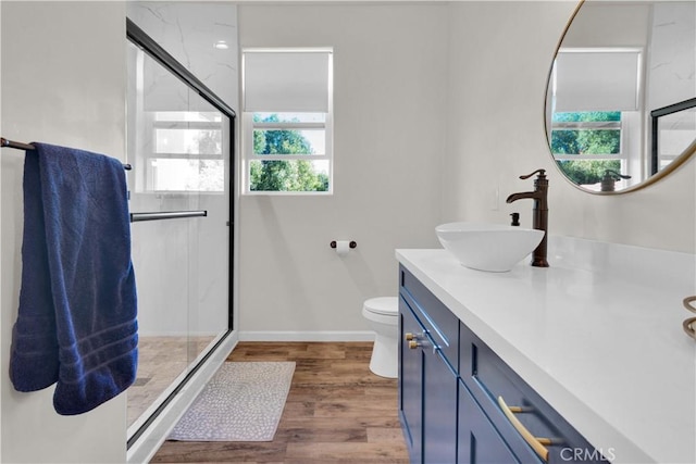 full bathroom with toilet, vanity, a shower stall, wood finished floors, and baseboards