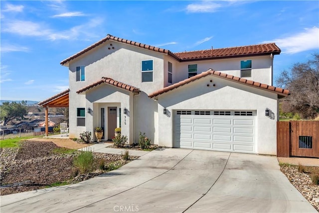 mediterranean / spanish home with a tile roof, stucco siding, fence, a garage, and driveway