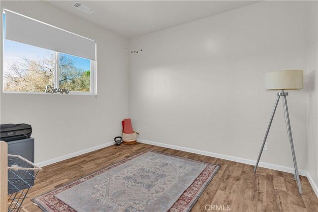 interior space with baseboards, visible vents, and wood finished floors