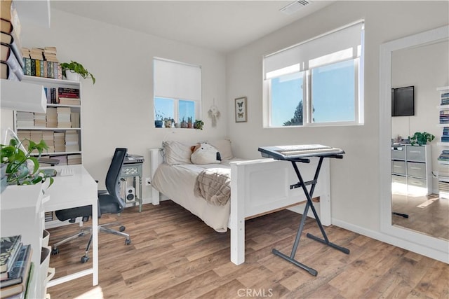 bedroom with wood finished floors, visible vents, and baseboards