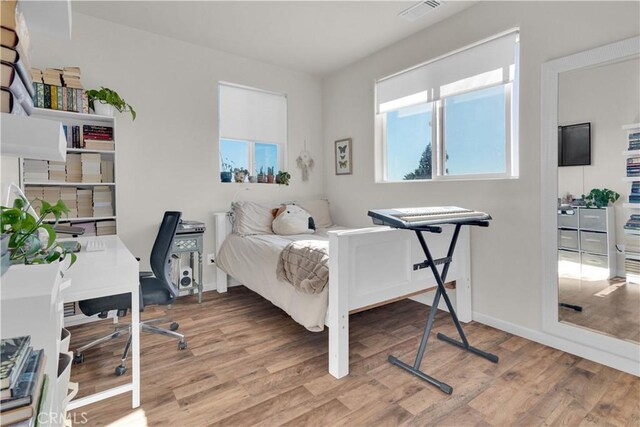 bedroom with visible vents, baseboards, and wood finished floors