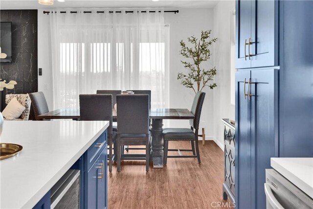 dining area featuring beverage cooler, baseboards, and wood finished floors