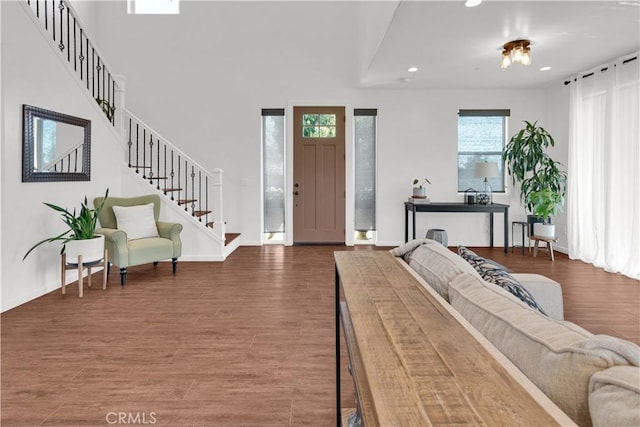 foyer with recessed lighting, a towering ceiling, stairway, wood finished floors, and baseboards