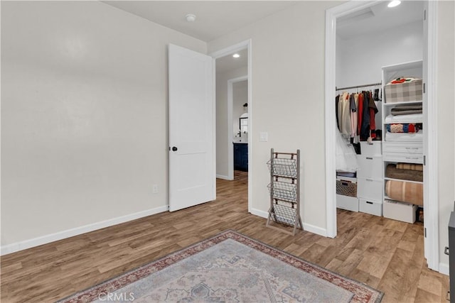 bedroom with a closet, recessed lighting, wood finished floors, and baseboards