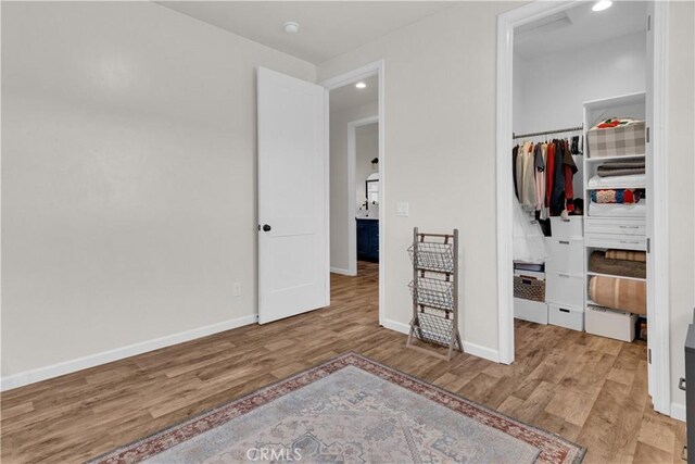 unfurnished bedroom featuring baseboards, recessed lighting, wood finished floors, and a closet