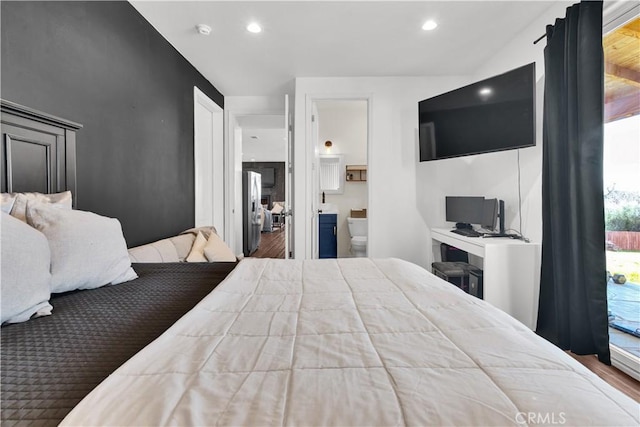 bedroom with recessed lighting, stainless steel fridge, wood finished floors, and ensuite bathroom