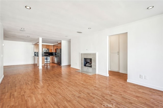 unfurnished living room with a tile fireplace and light hardwood / wood-style flooring