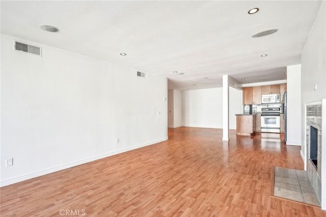 unfurnished living room with a fireplace and light hardwood / wood-style floors