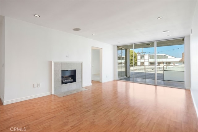 unfurnished living room featuring a fireplace, expansive windows, and light wood-type flooring