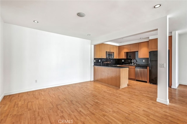 kitchen featuring sink, backsplash, light hardwood / wood-style floors, kitchen peninsula, and stainless steel appliances