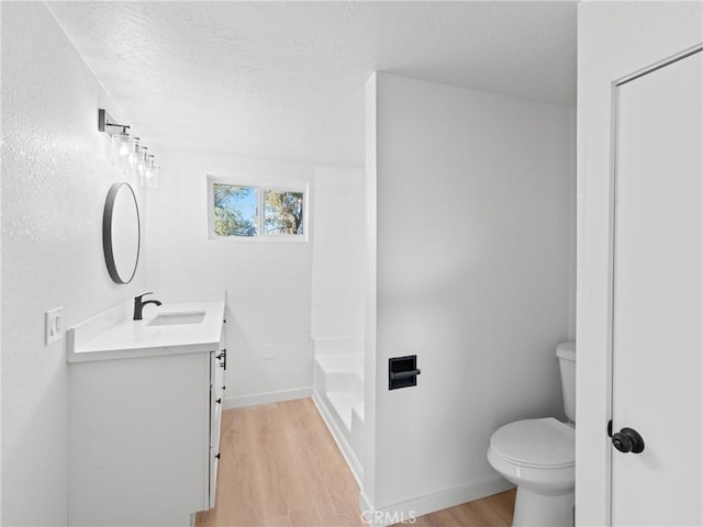 bathroom featuring toilet, vanity, a bath, and hardwood / wood-style flooring