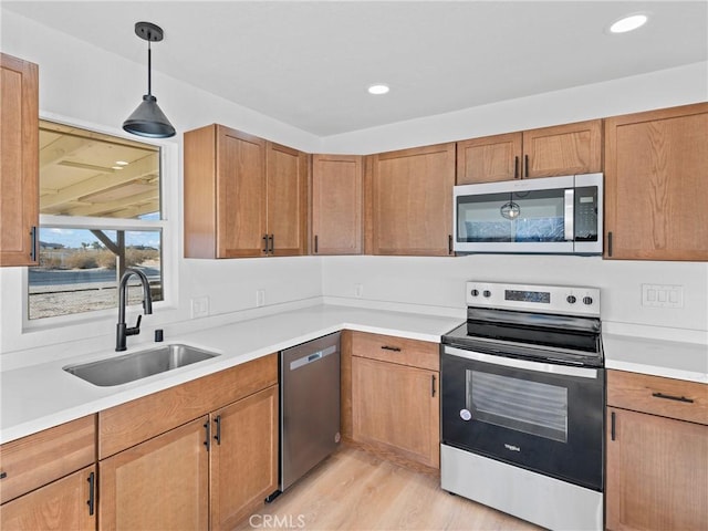 kitchen featuring hanging light fixtures, appliances with stainless steel finishes, sink, and light hardwood / wood-style floors