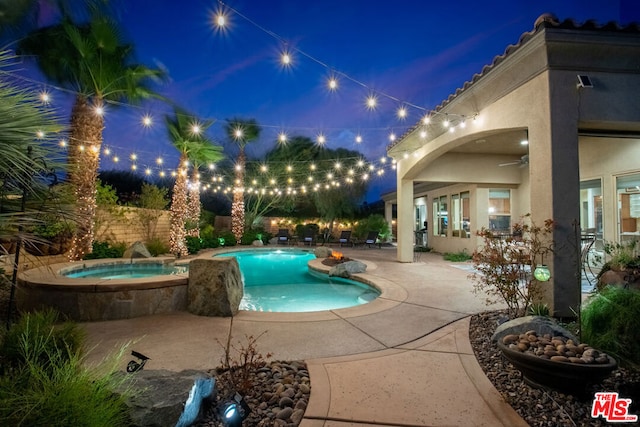 pool at twilight featuring ceiling fan, a patio area, and an in ground hot tub