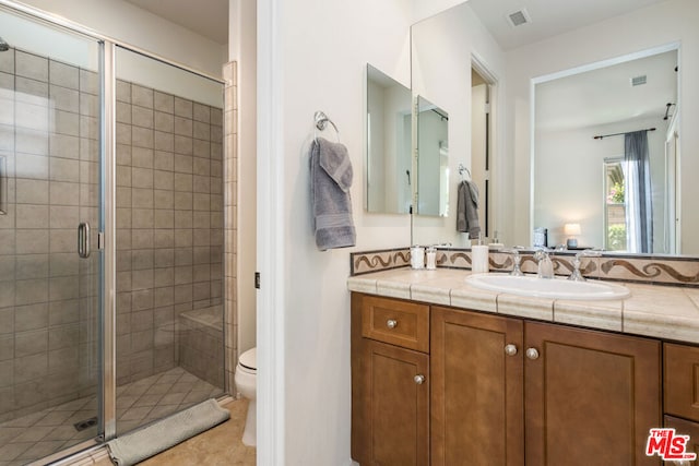 bathroom featuring toilet, a shower with door, vanity, and tile patterned flooring