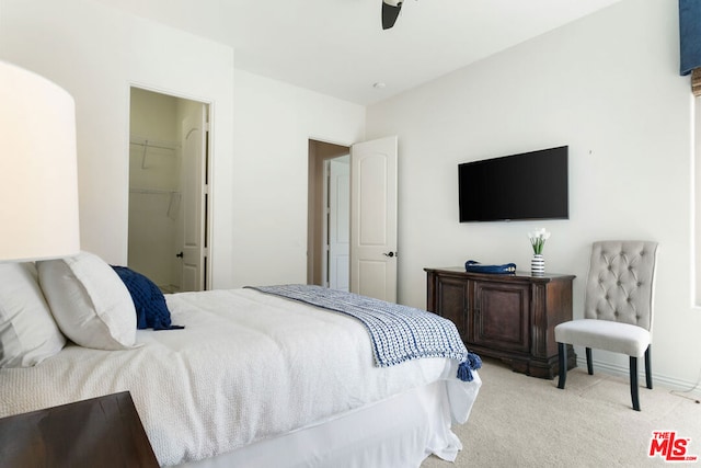 bedroom featuring ceiling fan, a closet, a spacious closet, and light carpet