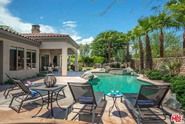 view of swimming pool with ceiling fan, a patio area, and an in ground hot tub