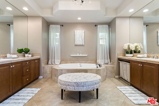 bathroom with vanity, tile patterned flooring, a notable chandelier, and a relaxing tiled tub