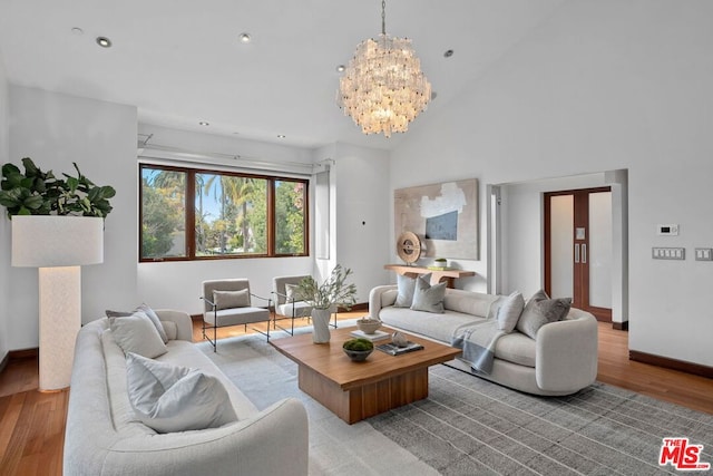 living room with a notable chandelier, high vaulted ceiling, and light hardwood / wood-style flooring