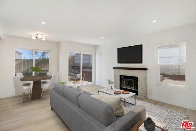 living room featuring a brick fireplace and light hardwood / wood-style flooring