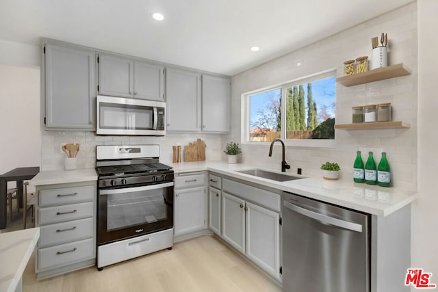 kitchen featuring appliances with stainless steel finishes, gray cabinets, sink, and light hardwood / wood-style flooring