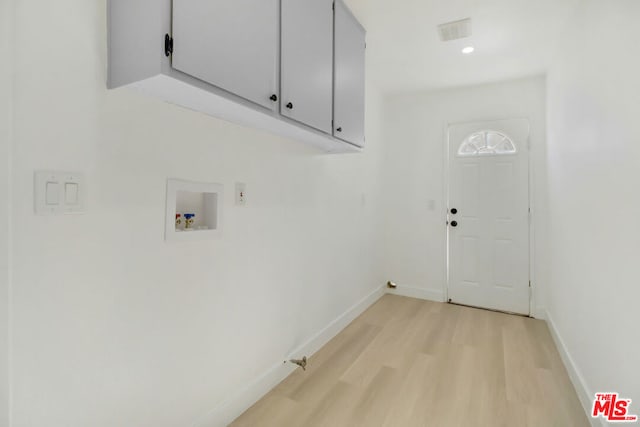 washroom with cabinets, hookup for a washing machine, and light hardwood / wood-style floors