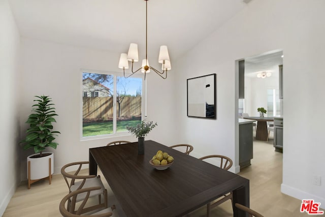 dining area featuring vaulted ceiling, a chandelier, and light hardwood / wood-style floors