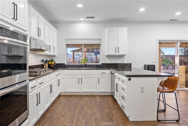 kitchen featuring a breakfast bar, white cabinetry, sink, and kitchen peninsula