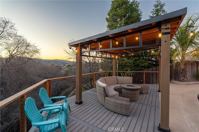 deck at dusk featuring a mountain view and an outdoor living space with a fire pit