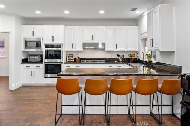 kitchen featuring sink, stainless steel appliances, white cabinetry, and a kitchen breakfast bar